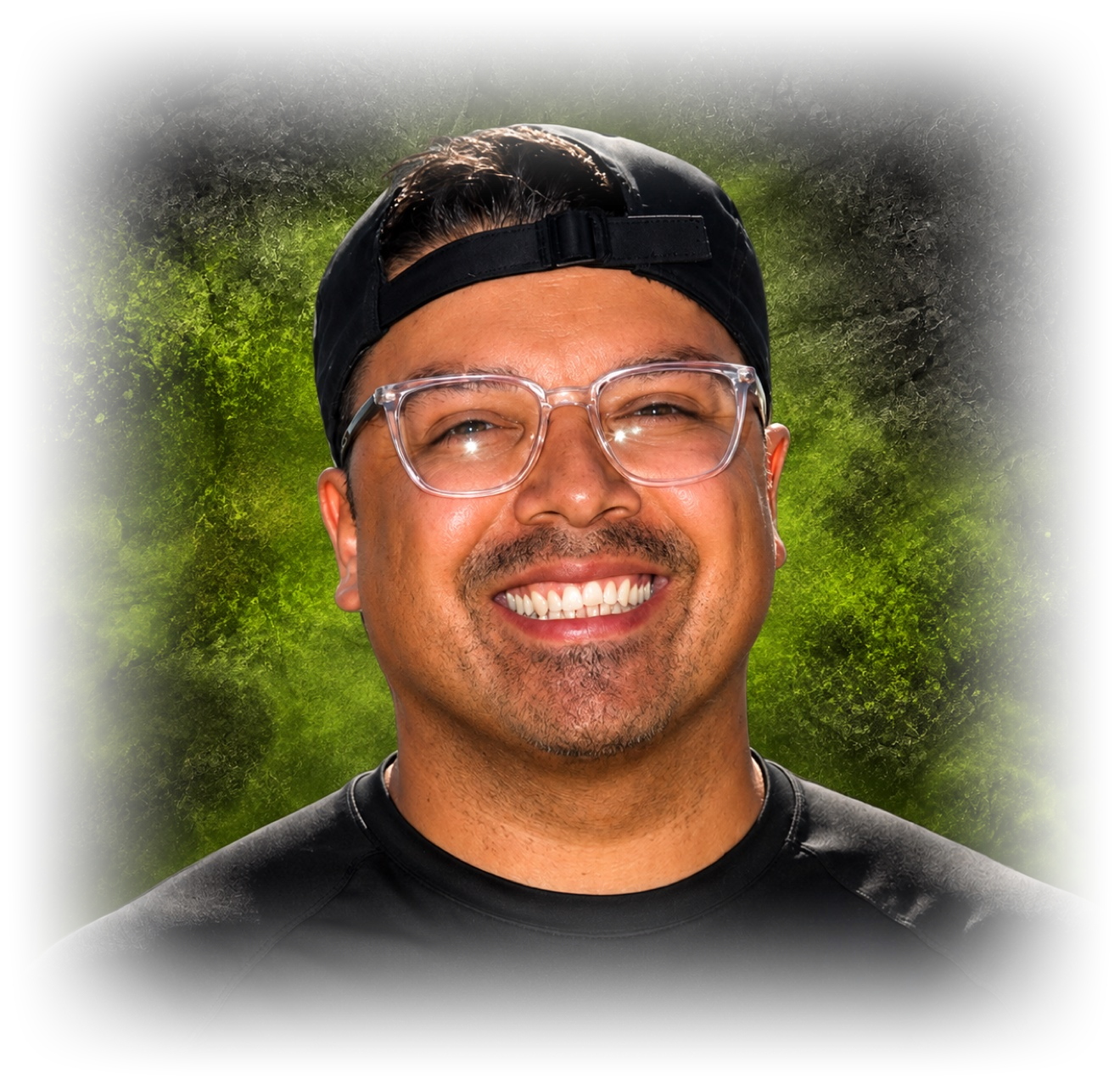 Joe Bordoy, owner of Bordoy Outdoor Services, smiling in clear glasses and a backwards black cap, against green smoke that fades into the black background