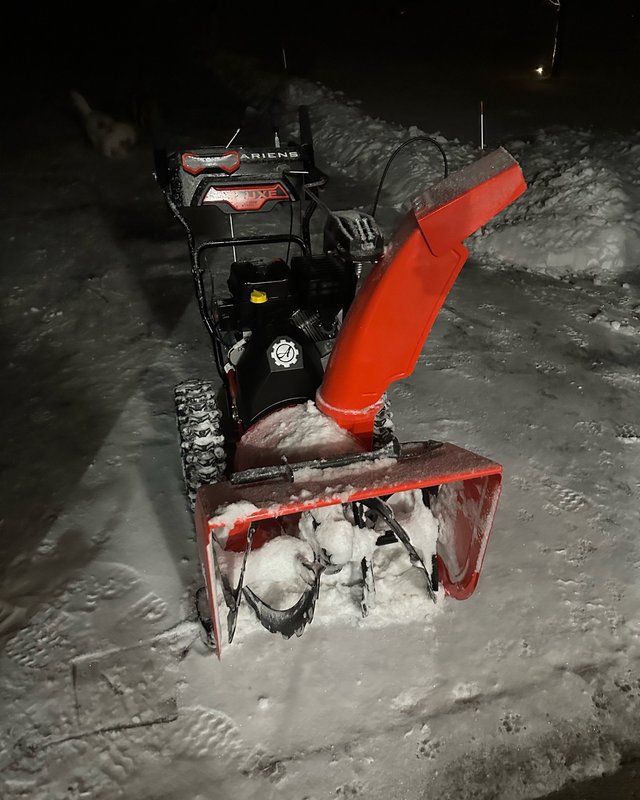 Joe's red Ariens snow blower at night, covered in fresh snow after clearing